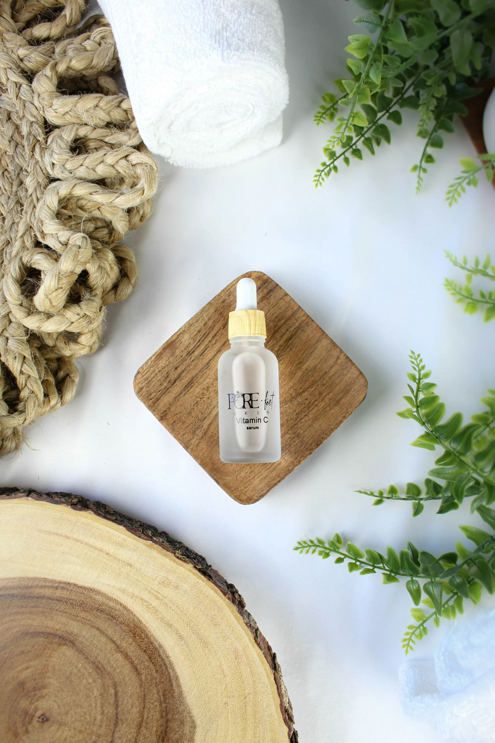 A small bottle of serum with greenery and towels.；第三方摄影参考