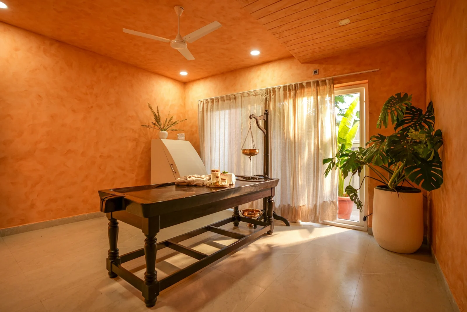 A massage table in a spa room with orange walls.；第三方摄影参考